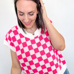 Woman wearing a pink and white checkered top against a plain background