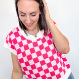 Woman wearing a pink and white checkered top against a plain background