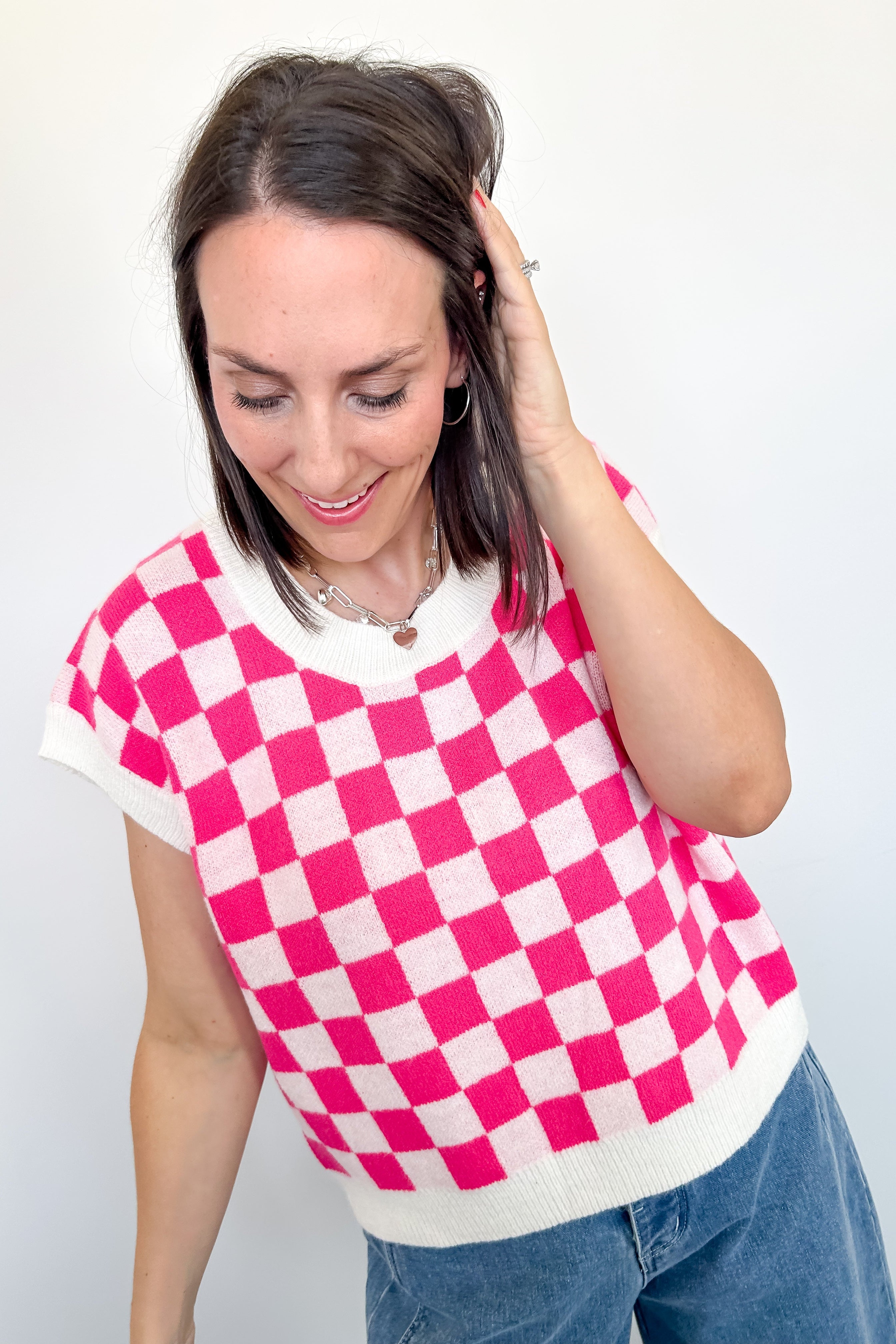 Woman wearing a pink and white checkered top against a plain background