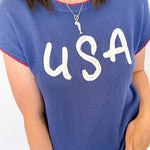 Person wearing a blue sweater with 'USA' printed on it against a white background