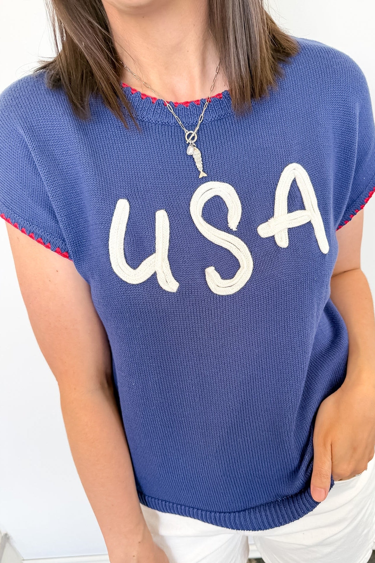 Person wearing a blue sweater with 'USA' printed on it against a white background