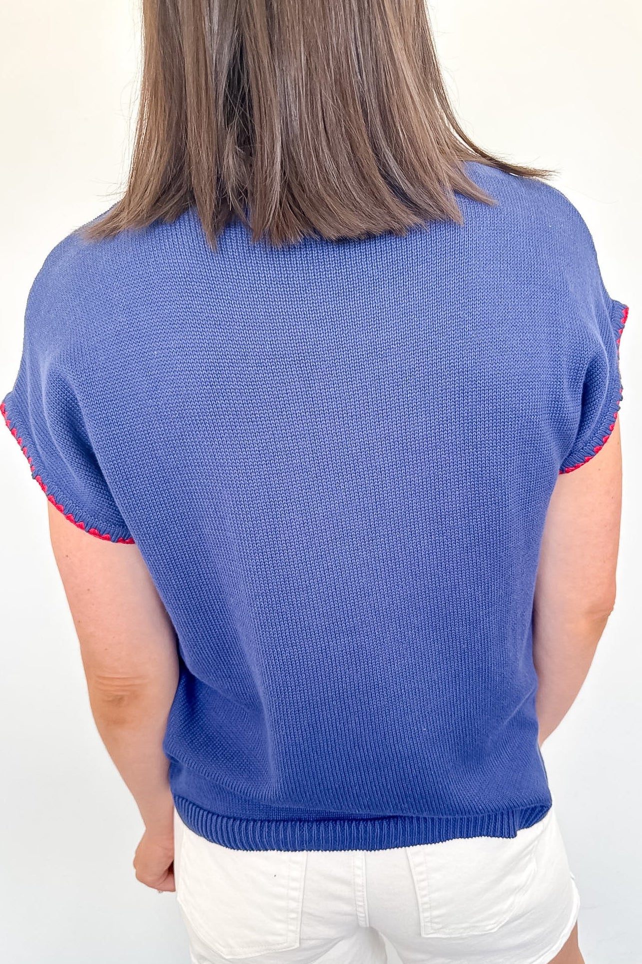 Person wearing a blue sweater with red trim on a white background