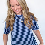 Woman wearing a blue and white striped shirt and jeans against a white background
