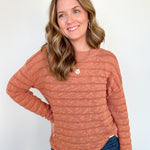 Woman wearing an orange sweater with necklace.