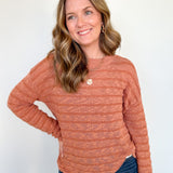 Woman wearing an orange sweater with necklace.