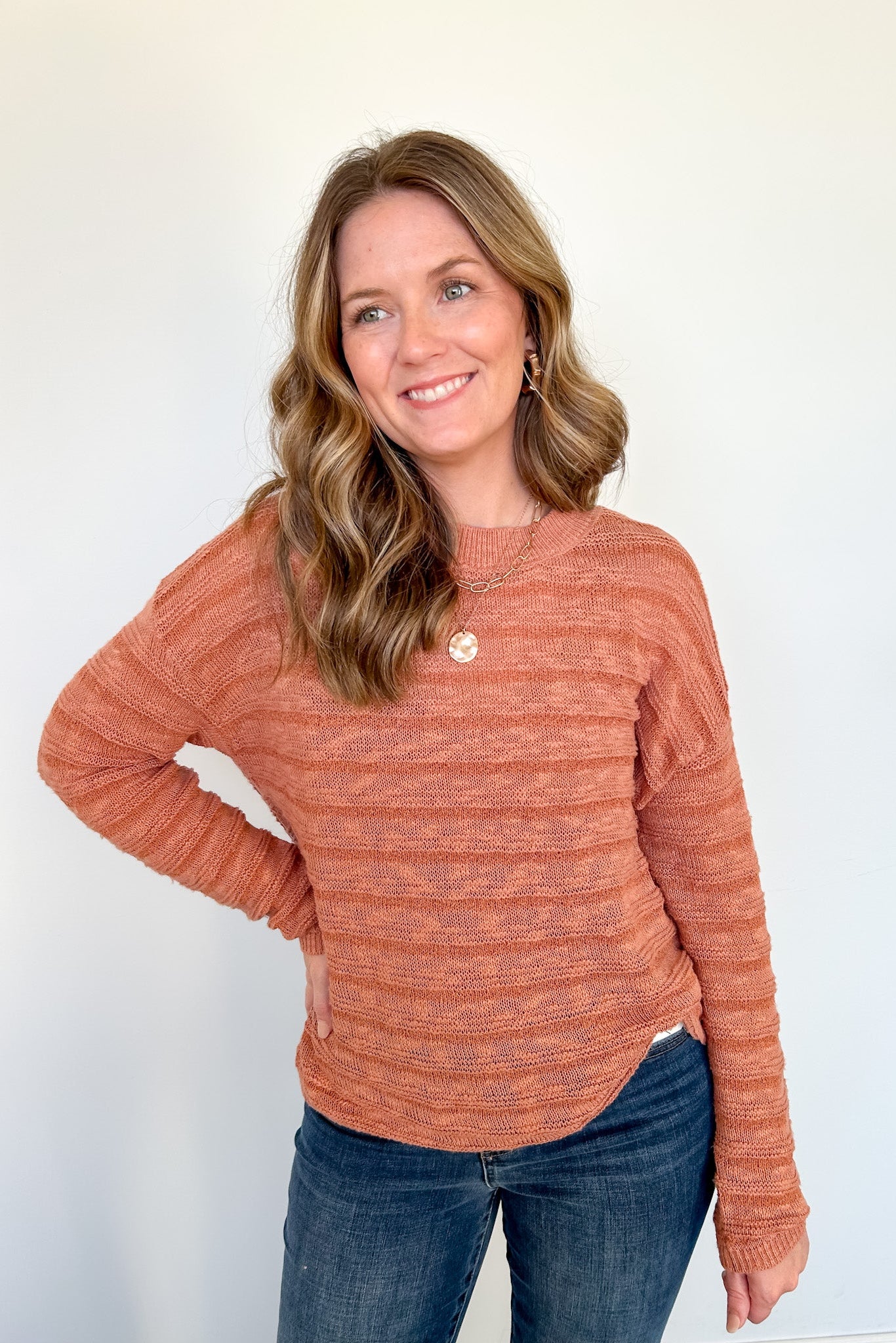 Woman wearing an orange sweater with necklace.