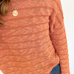 Person in striped orange sweater with necklace.