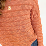 Person in striped orange sweater with necklace.