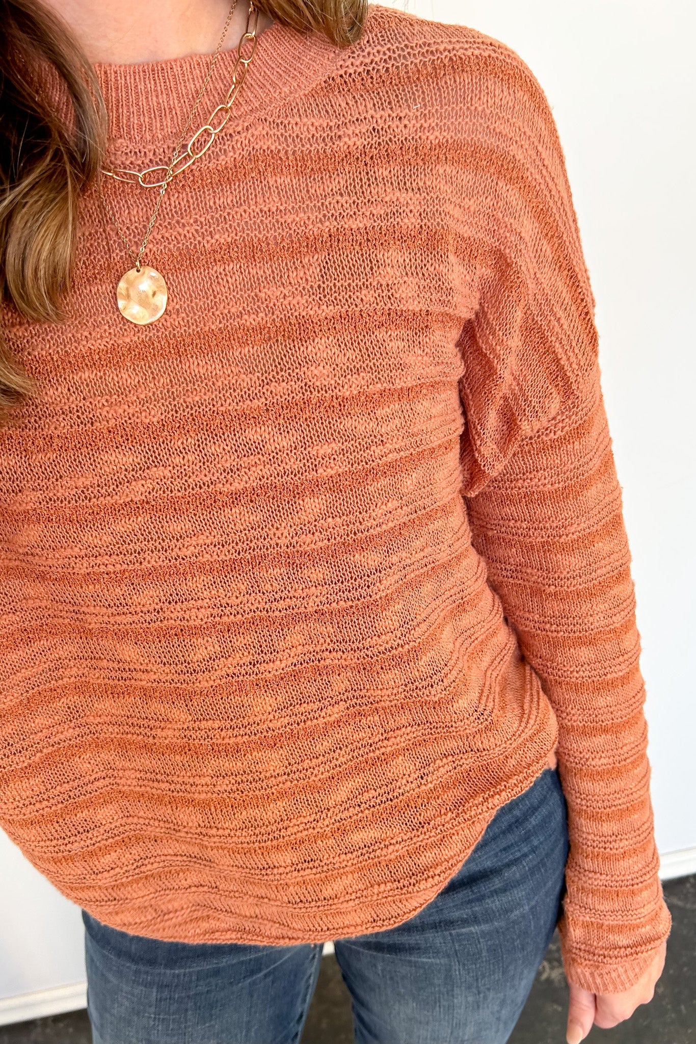 Person in striped orange sweater with necklace.
