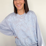 Woman wearing a light blue sweater with a subtle pattern against a plain background