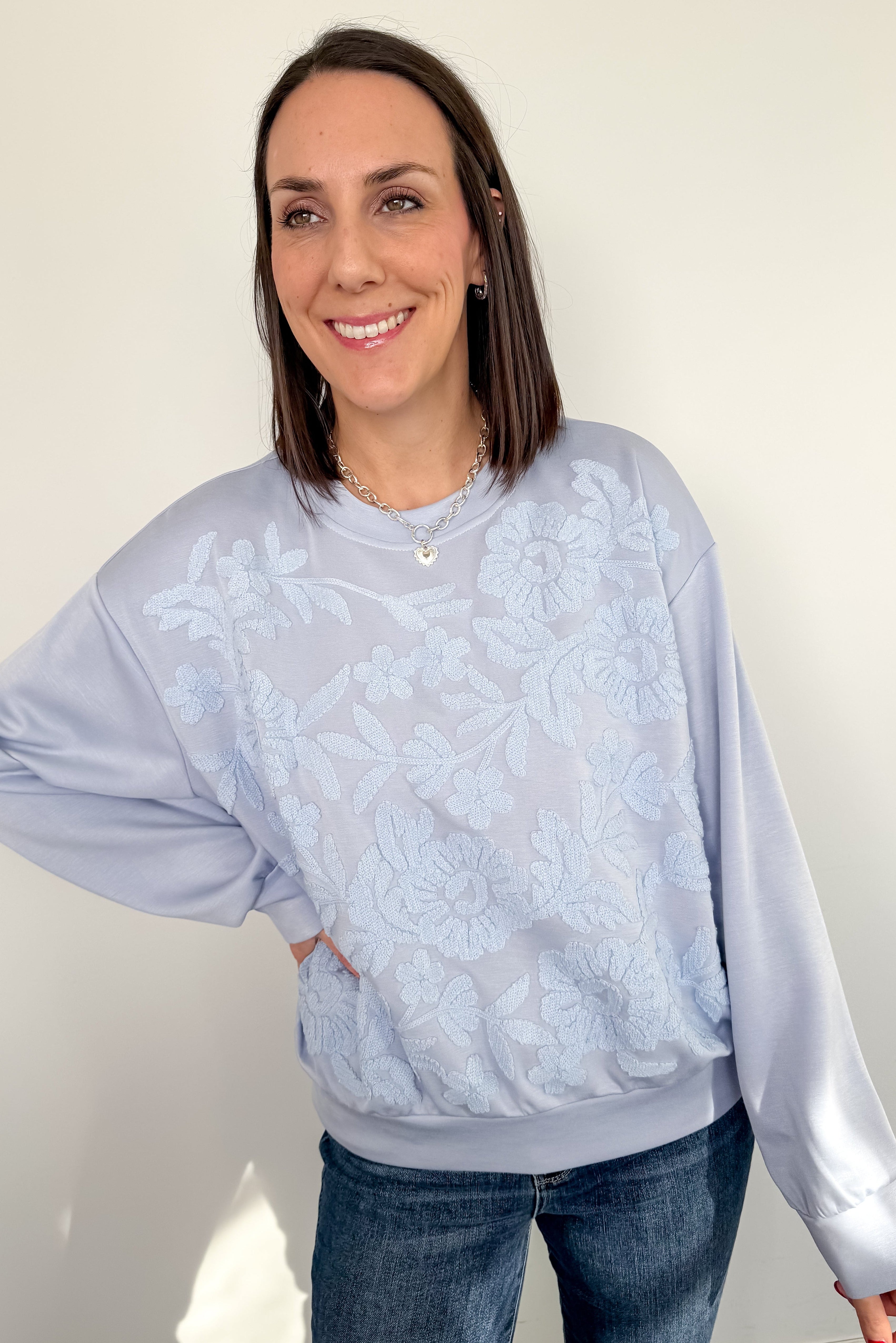 Woman wearing a light blue sweater with a subtle pattern against a plain background
