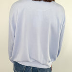 Person wearing a light blue sweater and jeans against a plain background