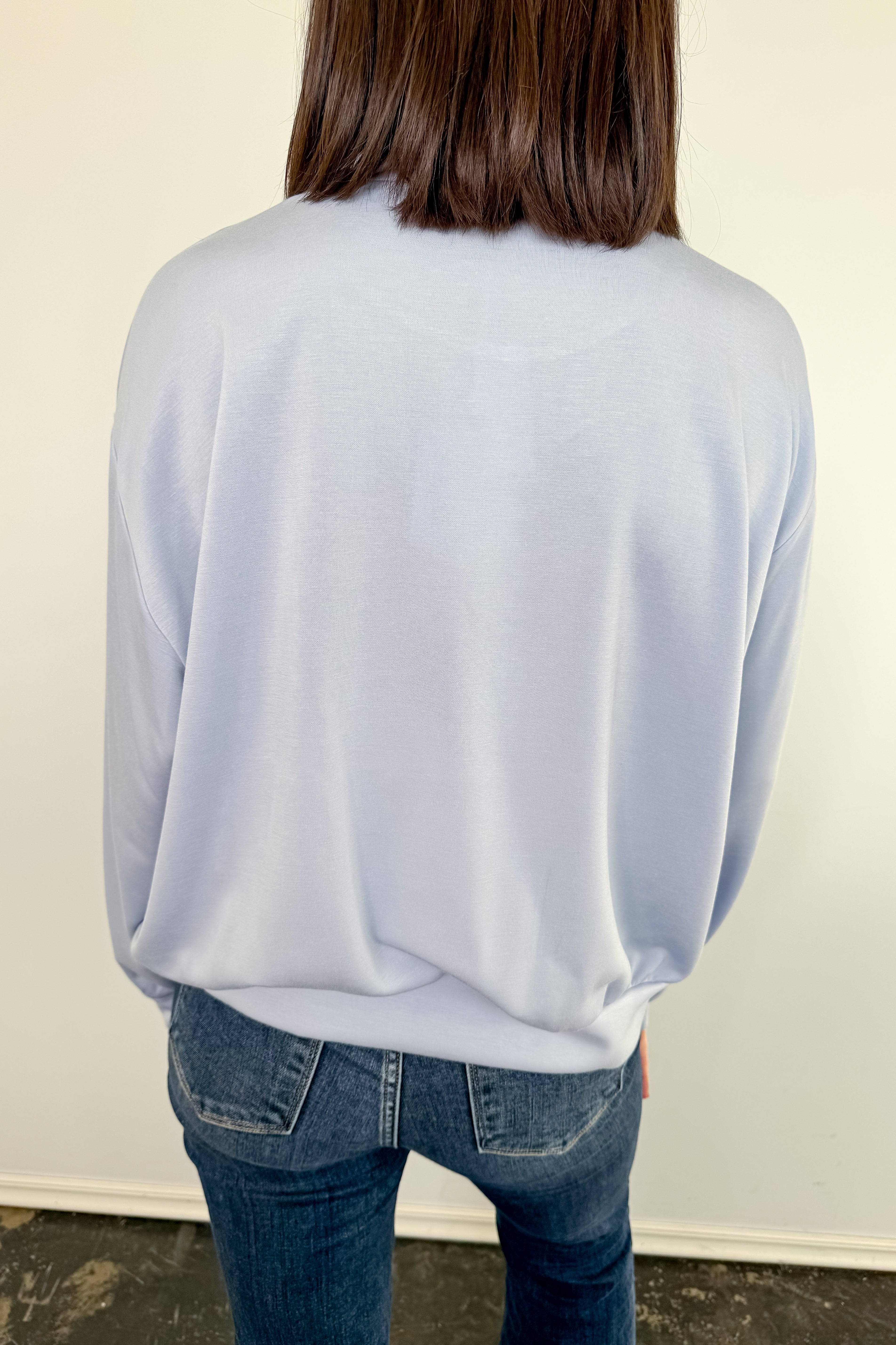 Person wearing a light blue sweater and jeans against a plain background
