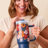 Woman holding a colorful tumbler with a floral design on a beige background