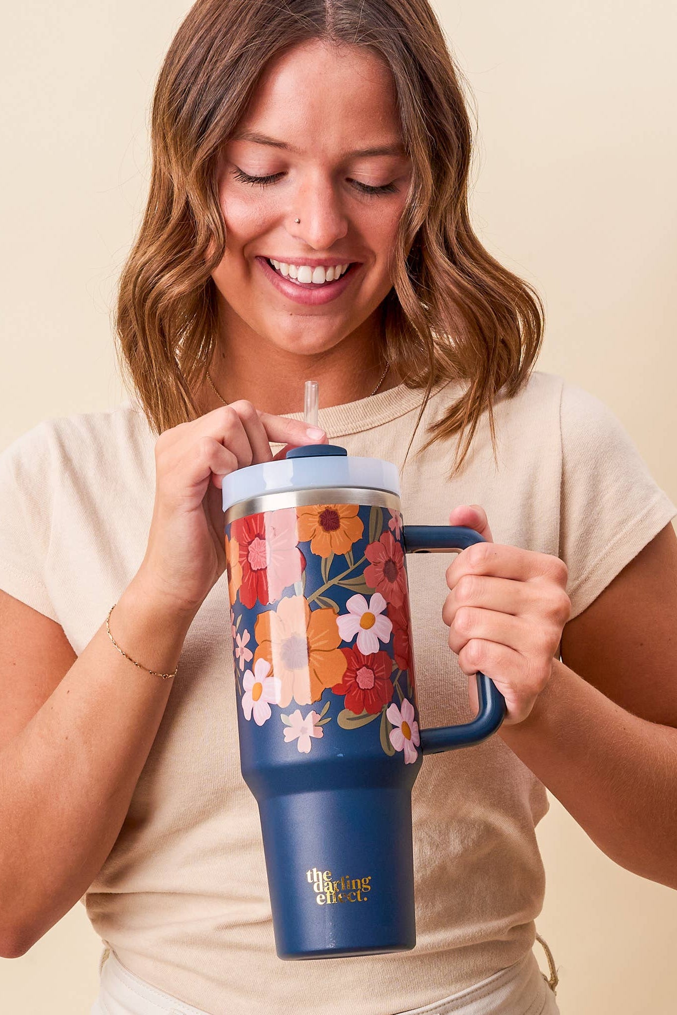Woman holding a colorful tumbler with a floral design on a beige background
