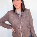 Woman wearing light brown jacket with her hand on her hip.