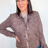 Woman wearing light brown jacket with her hand on her hip.