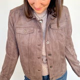 Woman wearing a brown suede jacket with a plain background