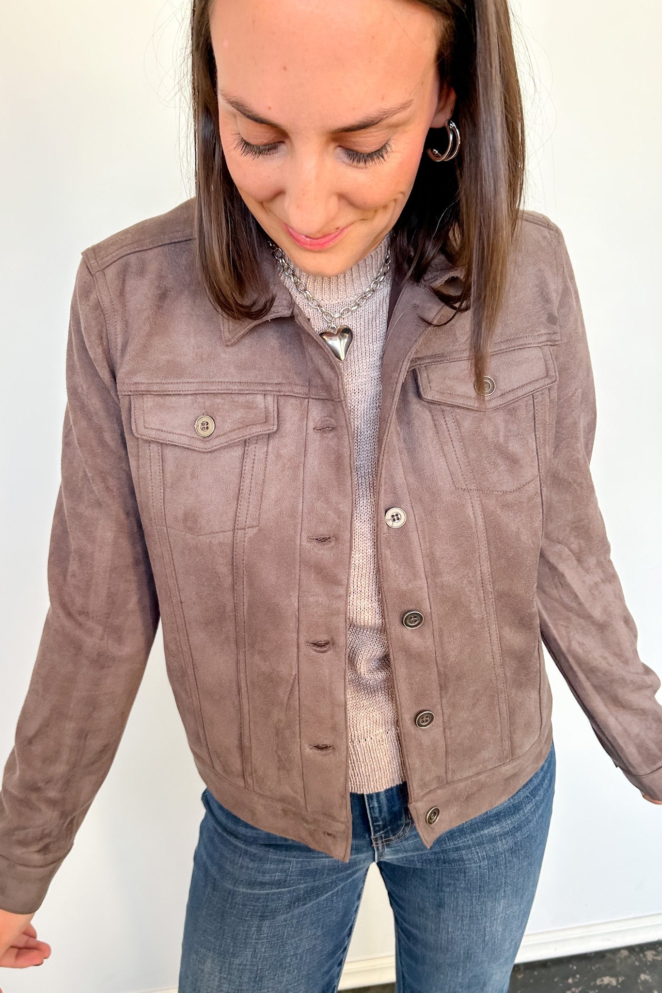 Woman wearing a brown suede jacket with a plain background