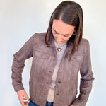 Person wearing a brown jacket against a plain background
