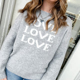 Person wearing a gray sweater with 'LOVE' text, standing indoors.