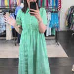 Woman in a green and white patterned dress with a collar and button front.