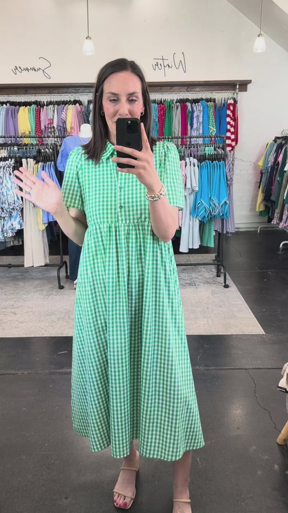 Woman in a green and white patterned dress with a collar and button front.